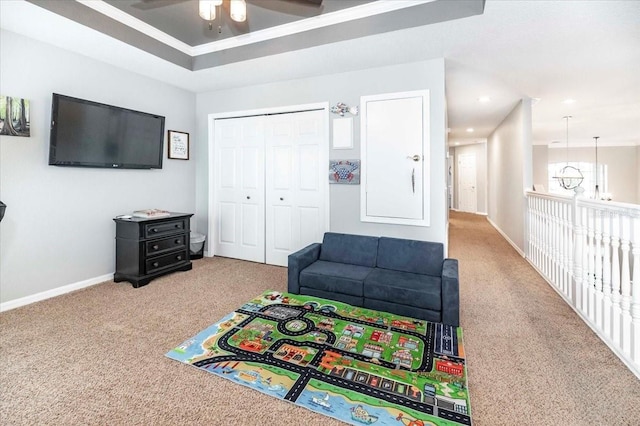 recreation room with a raised ceiling, carpet floors, and ceiling fan