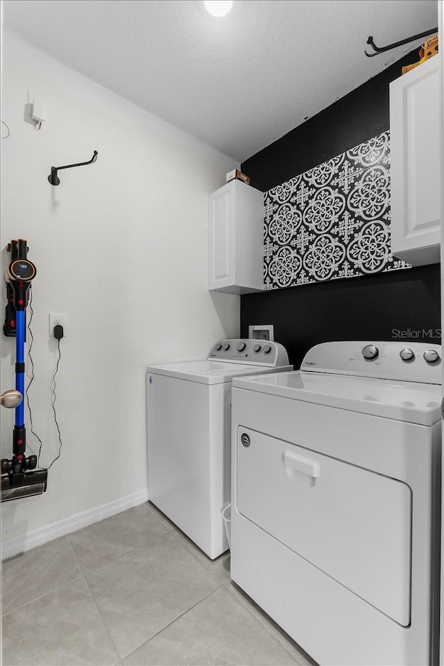 laundry room with separate washer and dryer, light tile patterned floors, cabinets, and a textured ceiling