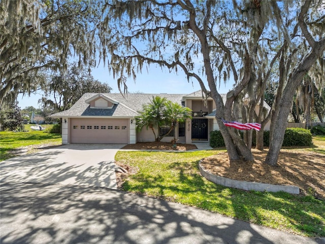 7410 Locksley Ln, Lakeland, FL 33809 - view of front of home with concrete driveway, a front lawn, a shingled roof, and an attached garage
