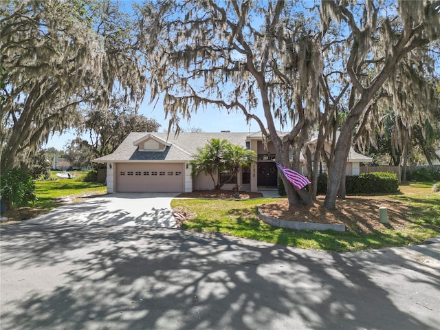 7410 Locksley Ln, Lakeland, FL 33809 - view of front facade featuring concrete driveway, a front lawn, a shingled roof, and an attached garage