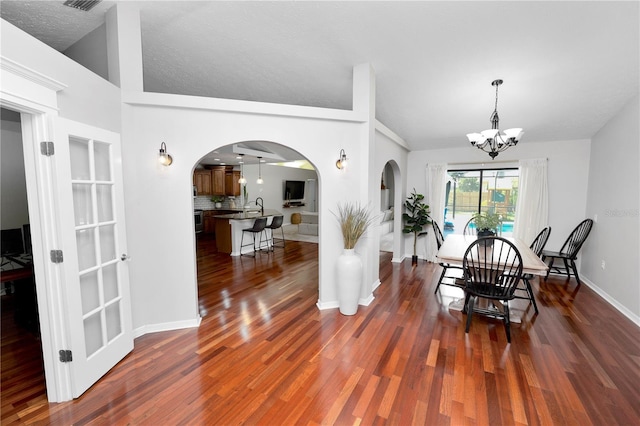 7410 Locksley Ln, Lakeland, FL 33809 - dining space with vaulted ceiling, arched walkways, a notable chandelier, and wood finished floors