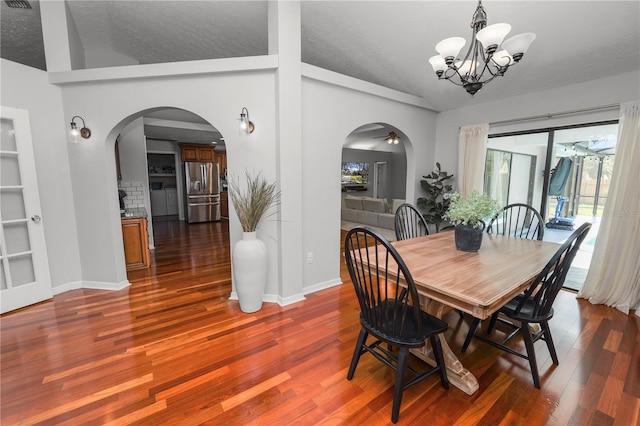 7410 Locksley Ln, Lakeland, FL 33809 - dining area featuring dark wood-style flooring, lofted ceiling, arched walkways, and a notable chandelier