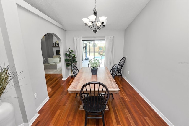 7410 Locksley Ln, Lakeland, FL 33809 - dining area with arched walkways, a notable chandelier, dark wood finished floors, and baseboards