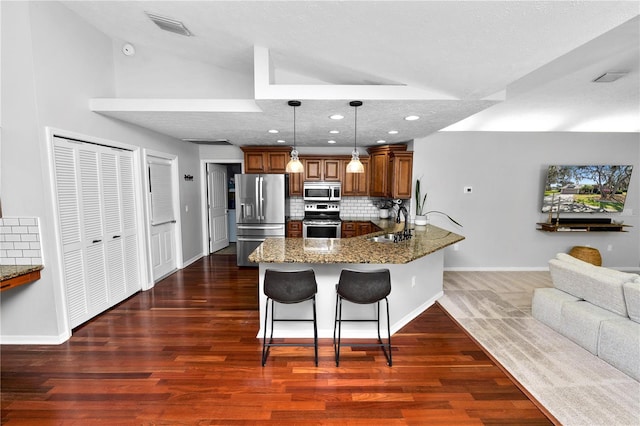 7410 Locksley Ln, Lakeland, FL 33809 - kitchen featuring vaulted ceiling, a peninsula, dark stone counters, and appliances with stainless steel finishes