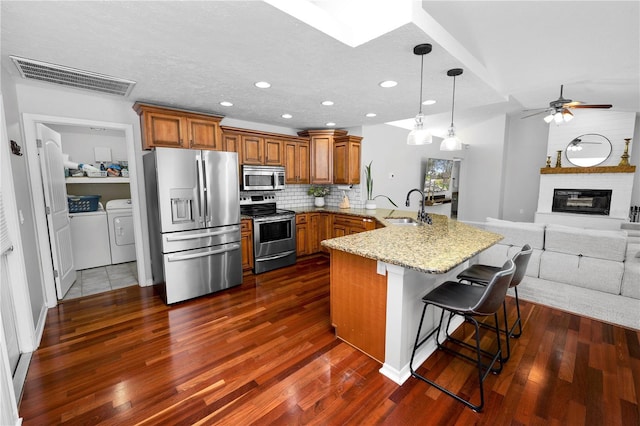 7410 Locksley Ln, Lakeland, FL 33809 - kitchen with a peninsula, brown cabinets, a sink, visible vents, and appliances with stainless steel finishes
