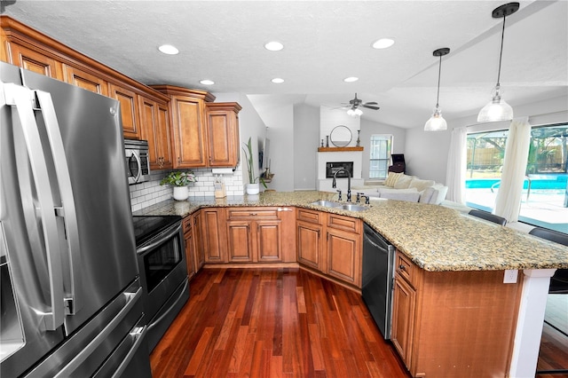 7410 Locksley Ln, Lakeland, FL 33809 - kitchen featuring a sink, a peninsula, stainless steel appliances, brown cabinetry, and a ceiling fan