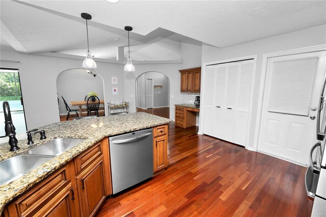 7410 Locksley Ln, Lakeland, FL 33809 - kitchen with stainless steel dishwasher, brown cabinetry, dark wood finished floors, a sink, and arched walkways