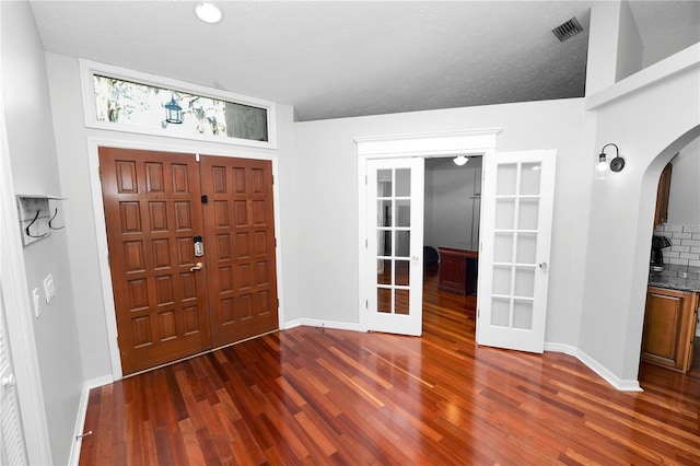 7410 Locksley Ln, Lakeland, FL 33809 - foyer entrance with wood finished floors, french doors, visible vents, baseboards, and arched walkways