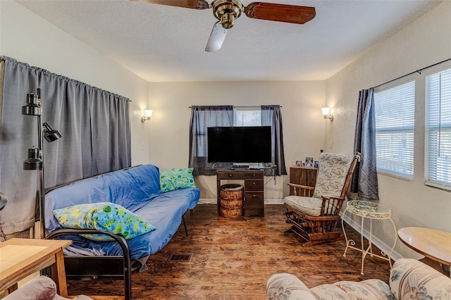 living room featuring ceiling fan, dark hardwood / wood-style flooring, and a textured ceiling