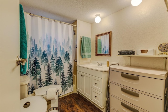 bathroom with vanity, toilet, hardwood / wood-style floors, and a textured ceiling