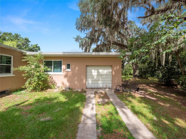 exterior space with a garage, a front yard, concrete driveway, and stucco siding