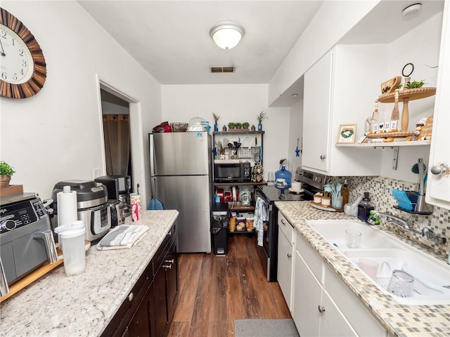 kitchen with light stone counters, appliances with stainless steel finishes, visible vents, and white cabinets