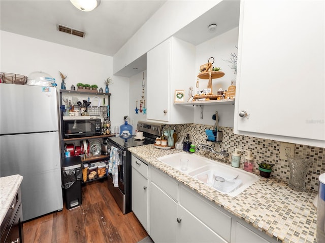 kitchen featuring dark wood-type flooring, a sink, visible vents, white cabinets, and appliances with stainless steel finishes