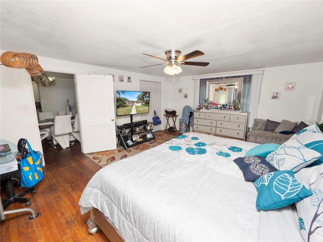 bedroom with dark wood-type flooring and ceiling fan with notable chandelier