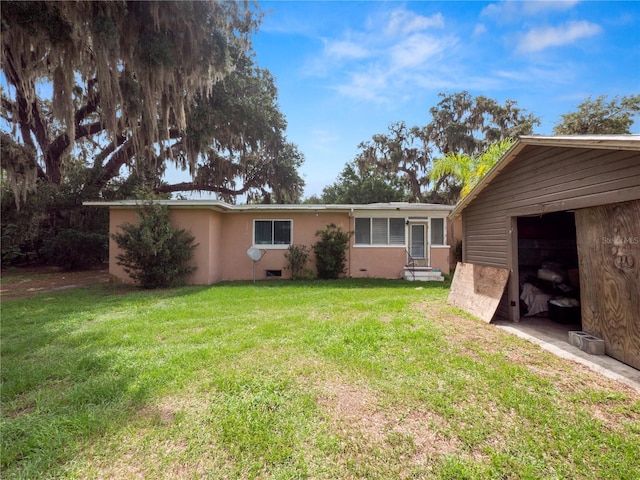 back of property with entry steps, a lawn, and stucco siding