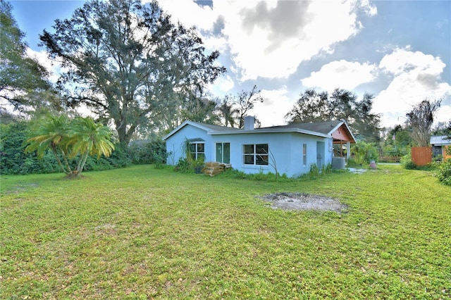 rear view of property with central AC and a lawn