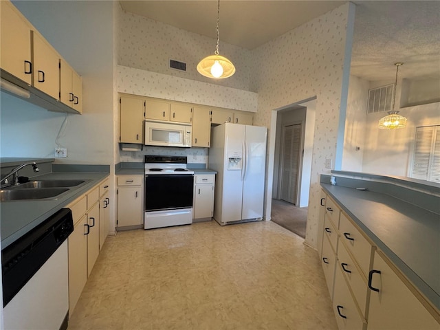 kitchen with pendant lighting, sink, a notable chandelier, cream cabinets, and white appliances