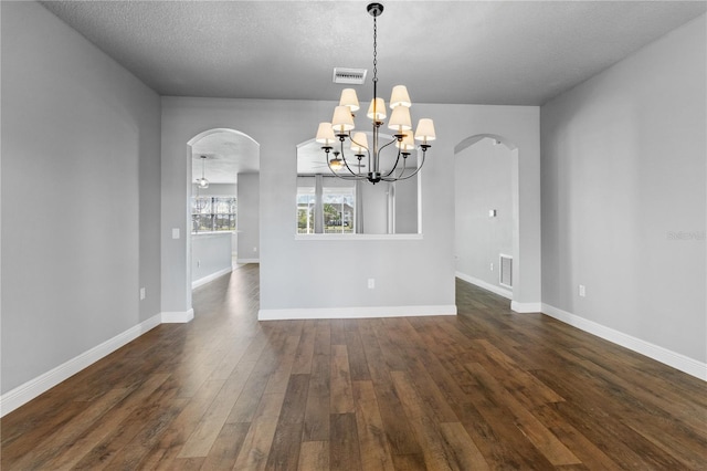 unfurnished dining area with dark wood-type flooring, arched walkways, visible vents, and baseboards