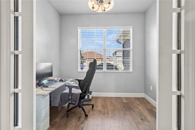 office space with a chandelier, a healthy amount of sunlight, baseboards, and wood finished floors