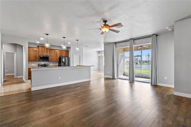 unfurnished living room featuring light wood-style floors, ceiling fan, baseboards, and arched walkways