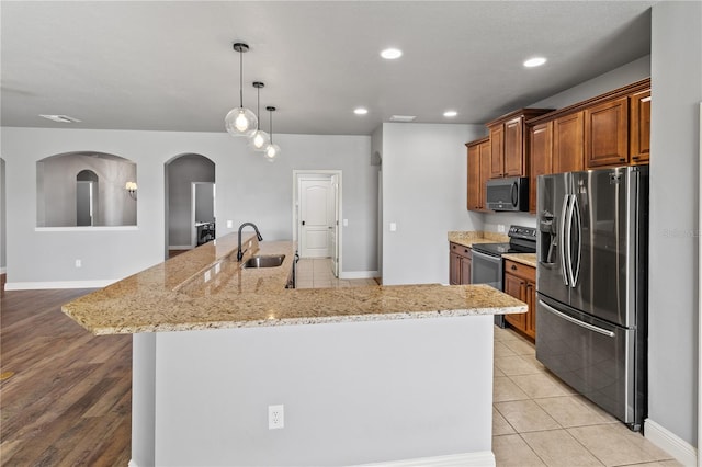 kitchen featuring brown cabinetry, a large island, light stone countertops, stainless steel appliances, and recessed lighting