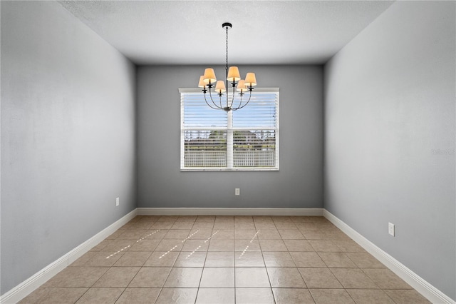 empty room featuring light tile patterned flooring, baseboards, and an inviting chandelier