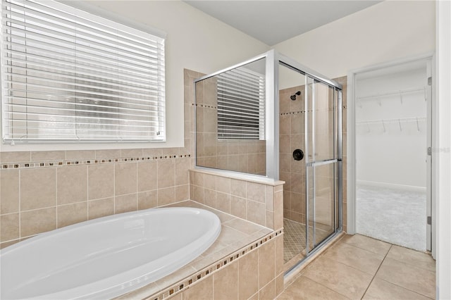 bathroom featuring a stall shower, a walk in closet, a bath, and tile patterned floors