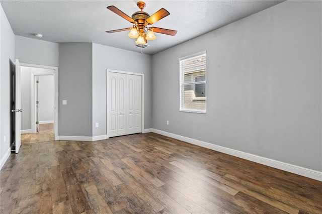 unfurnished bedroom featuring baseboards, a closet, visible vents, and wood finished floors