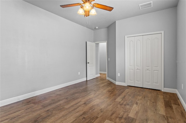 unfurnished bedroom featuring baseboards, a closet, visible vents, and wood finished floors