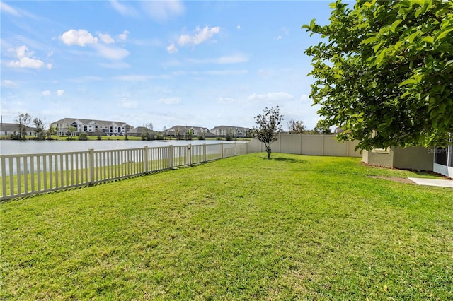 view of yard featuring a residential view, a water view, and a fenced backyard