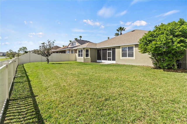 back of property featuring stucco siding, a fenced backyard, a sunroom, and a yard