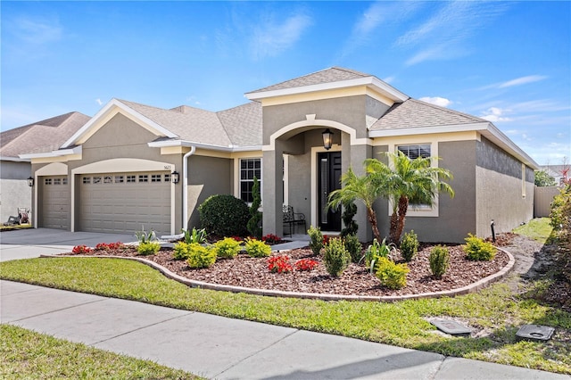 view of front facade with an attached garage, a shingled roof, concrete driveway, and stucco siding