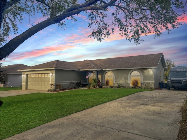 single story home with driveway, stucco siding, roof with shingles, an attached garage, and a front yard