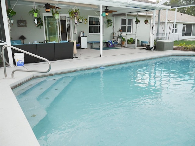 outdoor pool with a patio, glass enclosure, ceiling fan, outdoor lounge area, and central AC