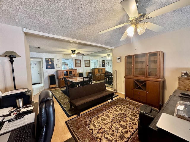 living room featuring hardwood / wood-style flooring, ceiling fan, and a textured ceiling