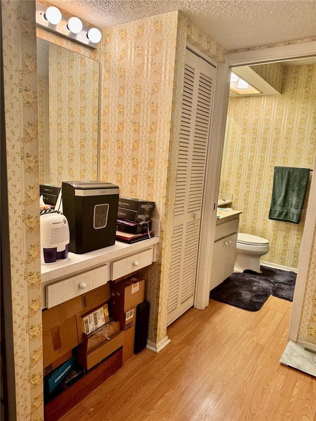 bathroom featuring vanity, hardwood / wood-style flooring, toilet, and a textured ceiling