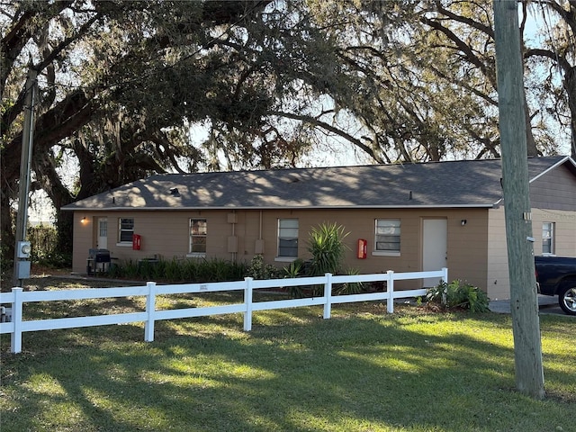 ranch-style home with a front lawn and a fenced front yard