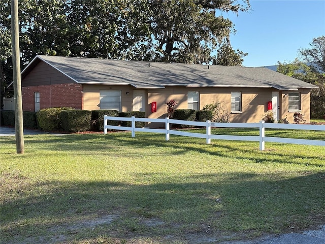 ranch-style home featuring a fenced front yard, brick siding, an attached garage, and a front lawn