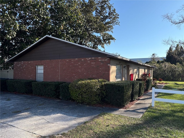 view of side of property featuring brick siding and a yard