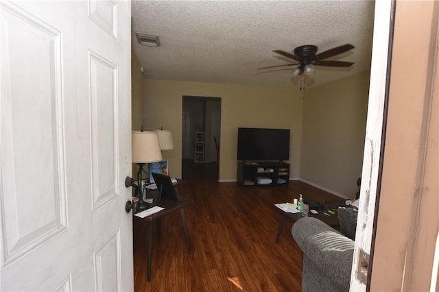 living area featuring visible vents, baseboards, dark wood-style floors, ceiling fan, and a textured ceiling