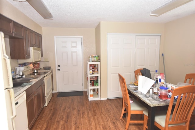 dining room with dark wood-type flooring, a textured ceiling, and baseboards