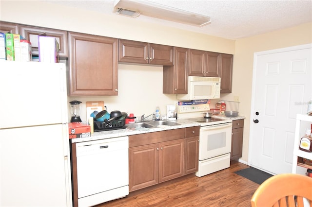 kitchen with white appliances, visible vents, dark wood-type flooring, light countertops, and a sink