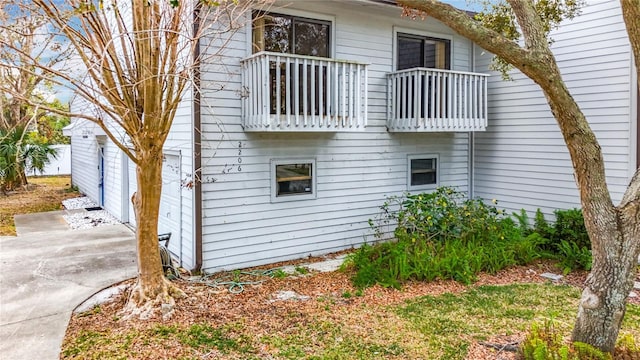 view of side of home with concrete driveway and a balcony