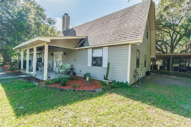 back of property with roof with shingles, a patio, a lawn, and a chimney