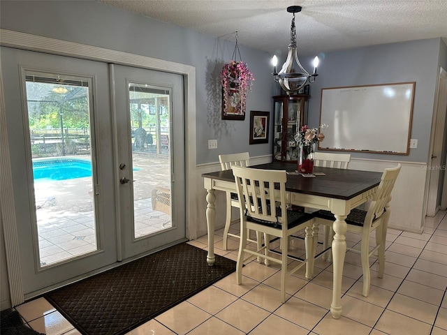 dining room with french doors, a notable chandelier, a textured ceiling, and light tile patterned floors