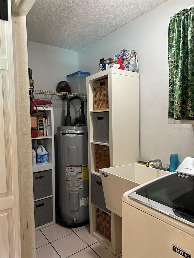 clothes washing area with water heater, light tile patterned flooring, washer / dryer, and a textured ceiling