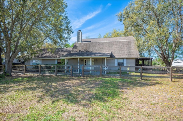 rear view of house featuring roof with shingles, a fenced front yard, a chimney, and a lawn