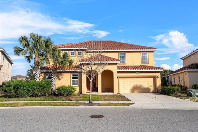 mediterranean / spanish-style home with driveway, a tile roof, an attached garage, central air condition unit, and stucco siding