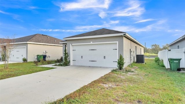 view of side of property with a garage, a lawn, and central AC