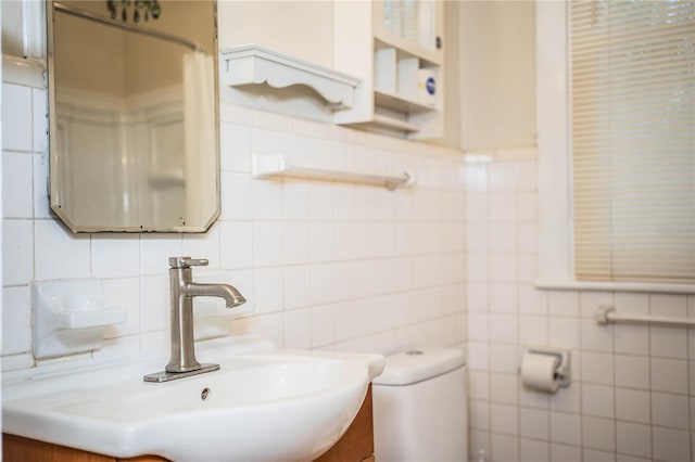 bathroom featuring sink, tile walls, and toilet